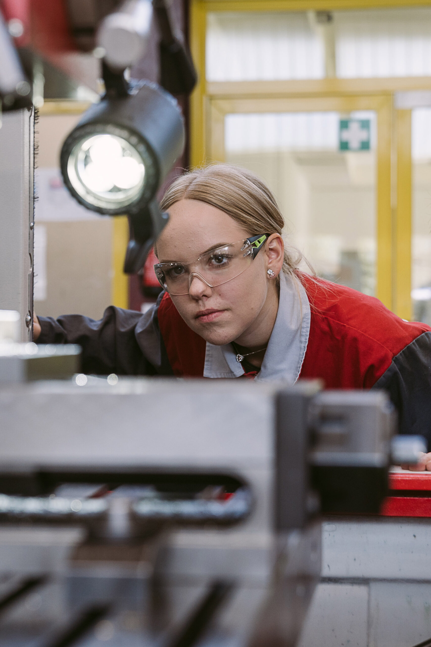 Ein Mädchen mit Schutzbrille bedient eine Maschine in der voestalpine